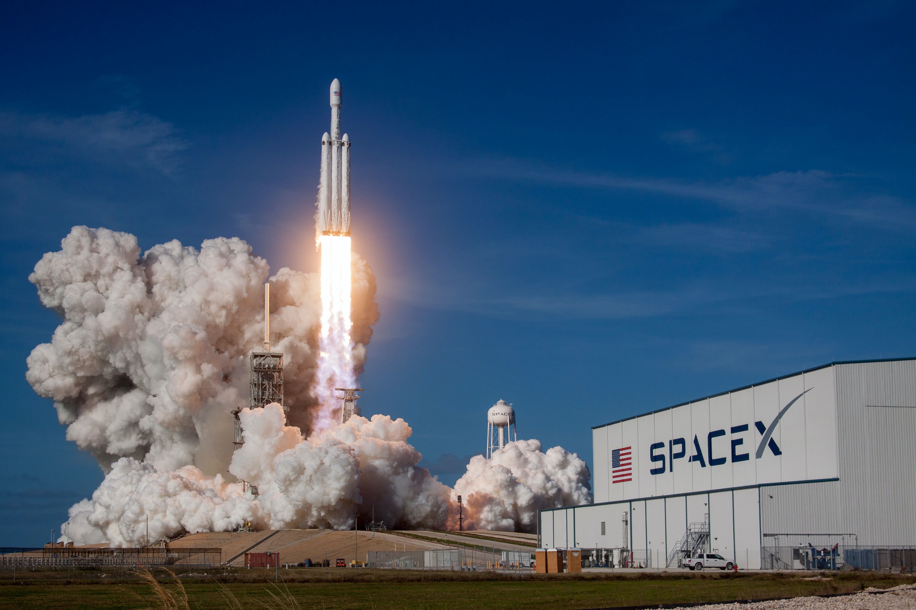 photo of a rocket on the ground at launch at SpaceX, with the smoke rolling and the flames bright as take off begins - time for launch