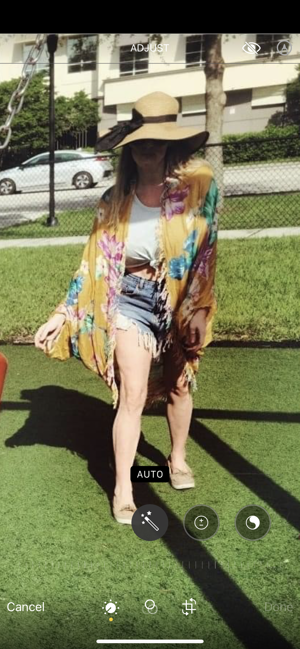 Katie in a big sun hat, beautiful bright shawl with vibrant colors, jean shorts and white tied t-shirt at the park pushing her son on the swings.(he is out of the picture) 