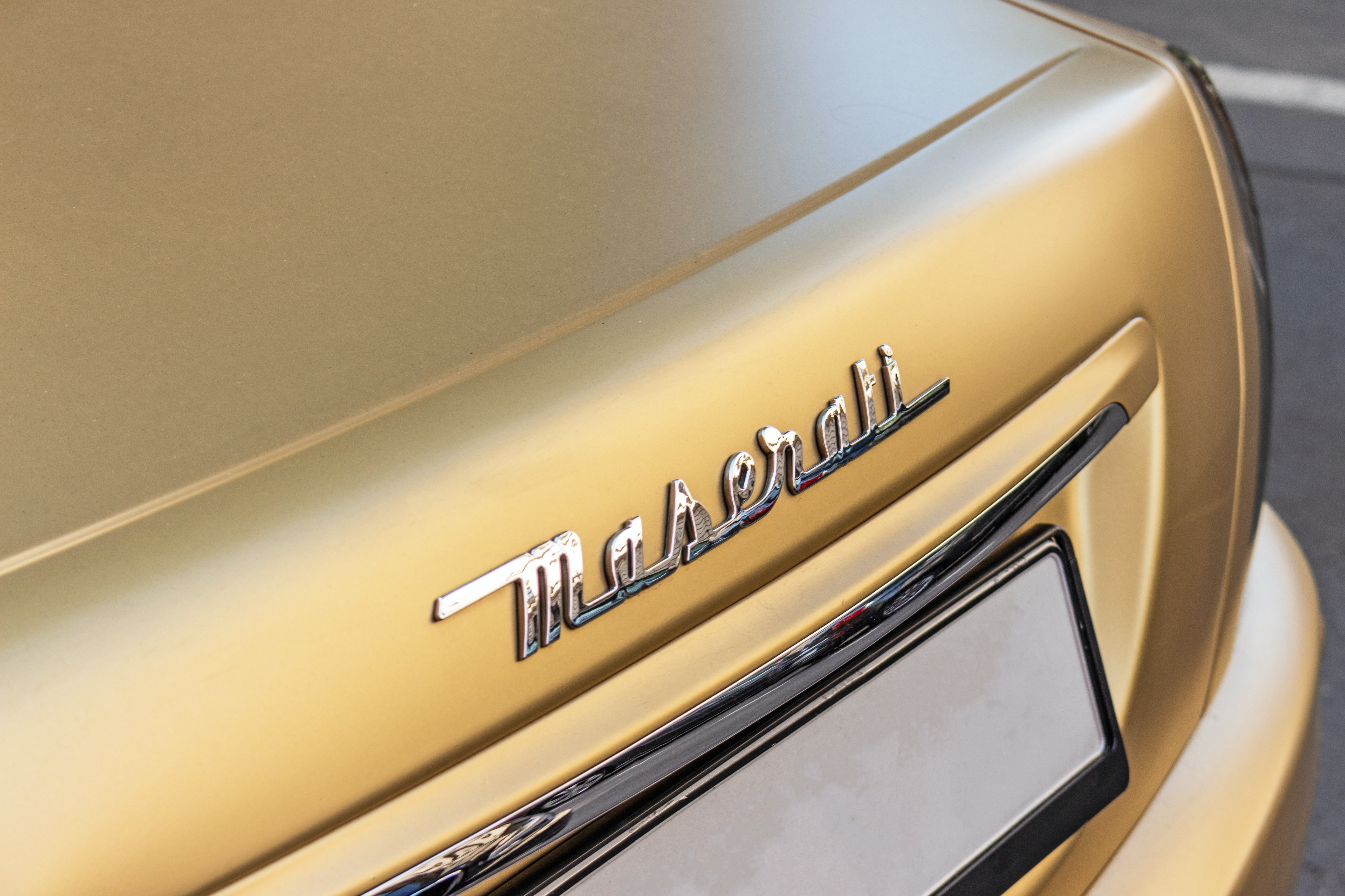 Image of the Maserati name on the back of a gold painted car 